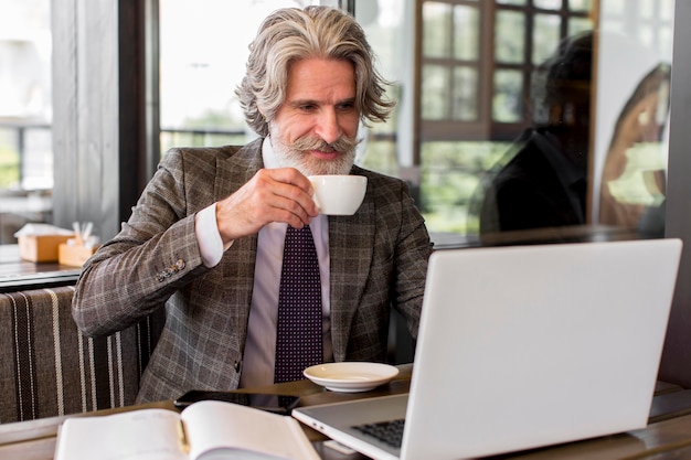 Elegante maschio maturo che gode del caffè in ufficio