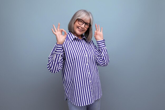 Stylish mature old lady in a trendy shirt on a bright studio background with copyspace