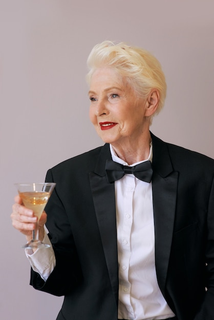 stylish mature sommelier senior woman in tuxedo with glass of sparkling wine