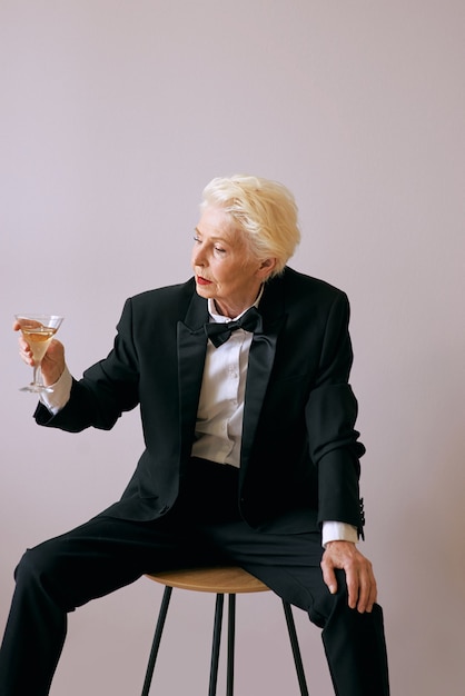 stylish mature sommelier senior woman in tuxedo with glass of wine