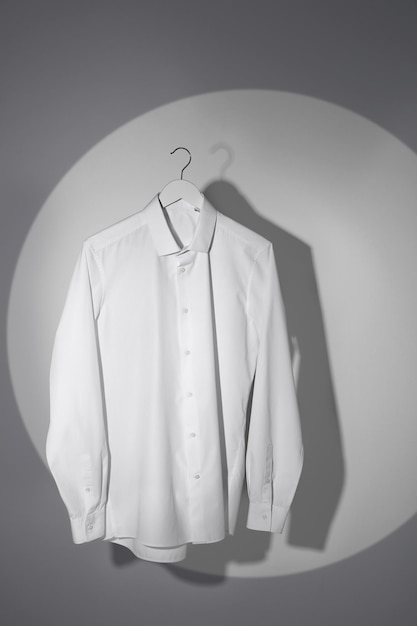 Stylish men's shirt hanging on light wall