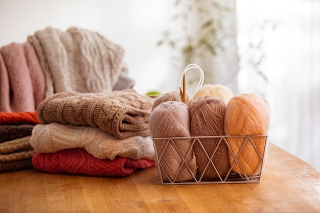 Stylish metal basket with balls of yarn at the table Hobby concept of knitting