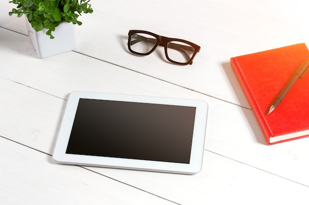 Stylish minimalistic workplace with tablet and notebook and glasses in flat lay style white background