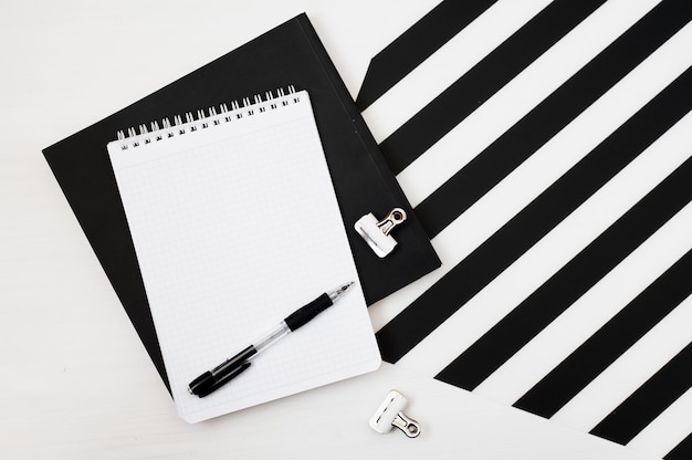 Stylish minimalistic workspace with notebook mock up, pencil on striped black and white ba