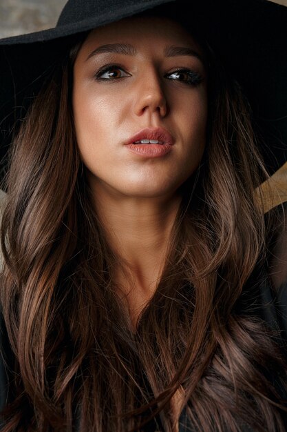 Stylish model with long shiny hair wearing hat. Closeup shot