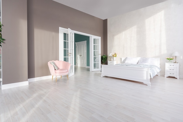 Stylish modern bedroom with a minimalistic design in a luxurious rich, expensive interior of an open-plan apartment in light colors.