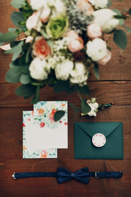 Foto elegante bouquet moderno e fiore all'occhiello dell'invito floreale e papillon su sfondo di legno vista dall'alto piatto disteso di inviti di nozze rustici imposta lo spazio mattutino dello sposo per il testo