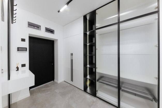 Stylish and modern bright corridor in a new house with a\
wardrobe and dark shelves