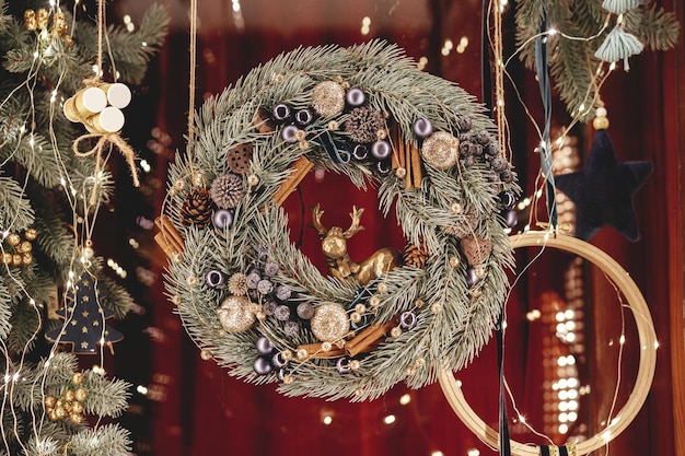 Photo stylish modern christmas wreath branches ornaments in lights in evening atmospheric magic time
