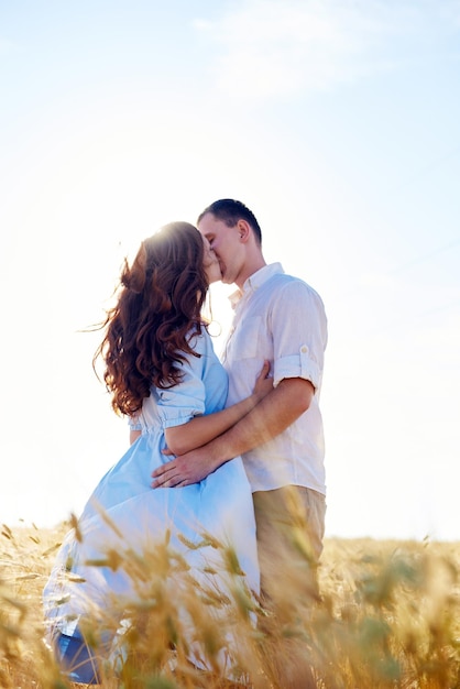 Stylish and modern couple kissing in a wheat field A young woman hugs her boyfriend and kisses each other The concept of passion and love