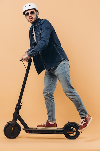 Stylish modern man in a helmet rides an electronic scooter photo in the studio