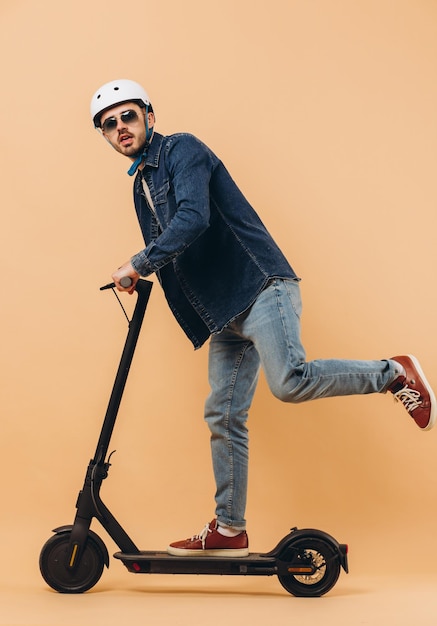 Stylish modern man in a helmet rides an electronic scooter photo in the studio