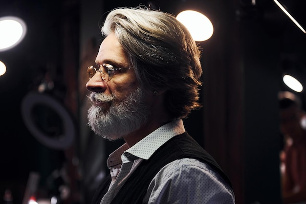 Foto l'uomo anziano moderno ed elegante con i capelli grigi e la barba è al chiuso