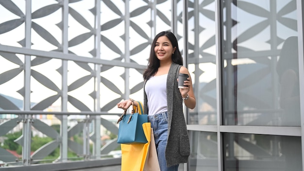 Stylish modern young woman with shopping bags walking outdoor during holiday sales season