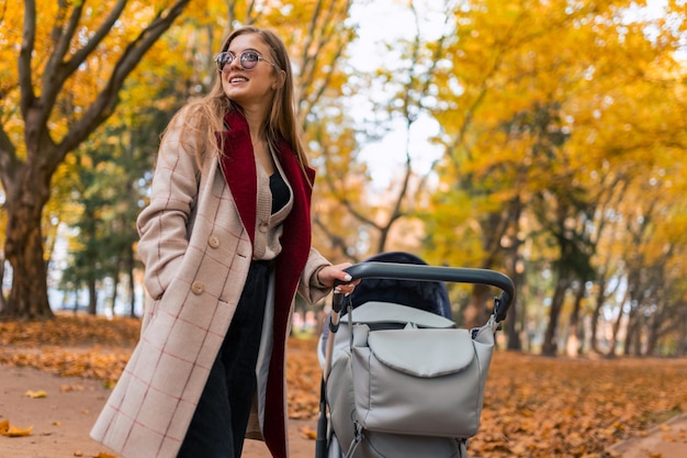 Stylish mom with stroller in autumn park