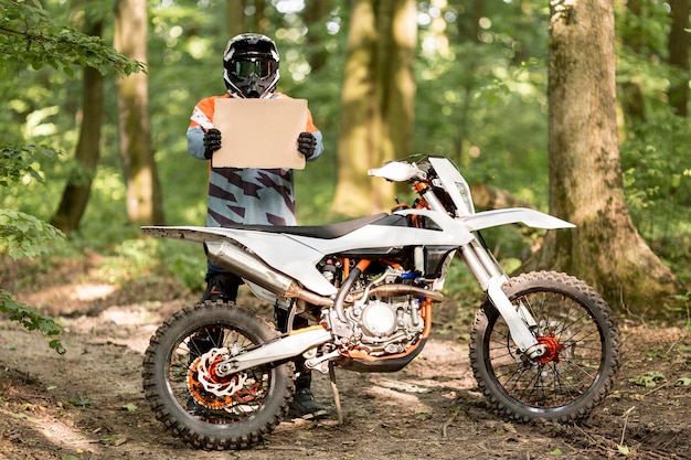 Photo stylish motorbike rider holding cardboard sign