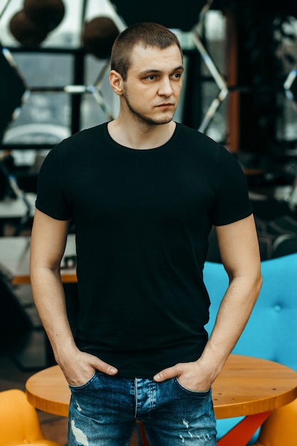 스튜디오에서 포즈 검은 티셔츠를 입고 세련된 근육질의 남자