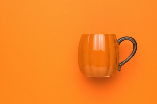 Photo stylish orange mug on a bright orange background.