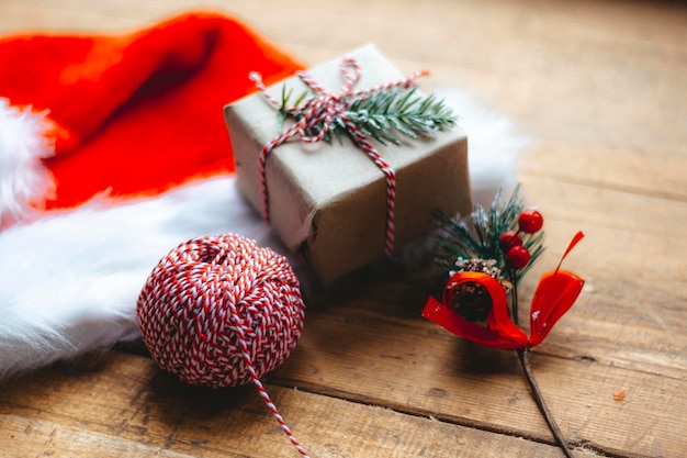 세련된 포장된 크리스마스 선물 상자, 산타클로스 모자, 소박한 나무 테이블에 가문비나무 장식이 있습니다. 분위기 있는 이미지. 즐거운 성탄절과 즐거운 휴일 보내세요, 새해 복 많이 받으세요