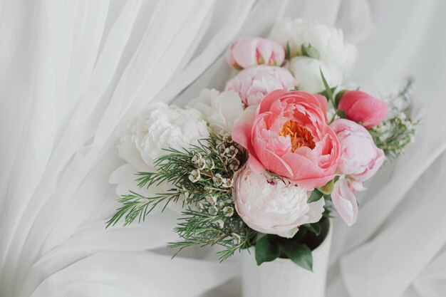 Stylish peonies bouquet on background of soft white fabric flowers in ceramic vase Mothers day