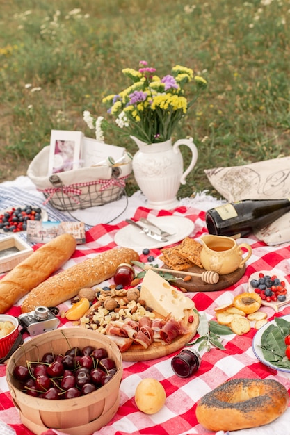 Stylish picnic on the green lawn. Fresh croissants and a teapot with tea on a bedspread near a wicker female hat. Instagram content