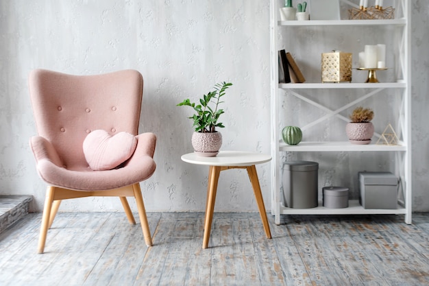 Stylish pink armchair with heart shaped pillow in a bright minimalist interior