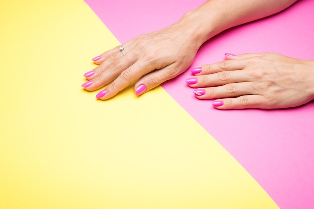 Stylish pink manicure on a yellow and pink background