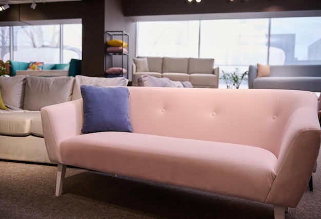 Stylish pink sofa with purple cushion in the showroom of\
upholstered furniture furniture store with sofas and couches on\
display for sale copy space furniture store showroom interior