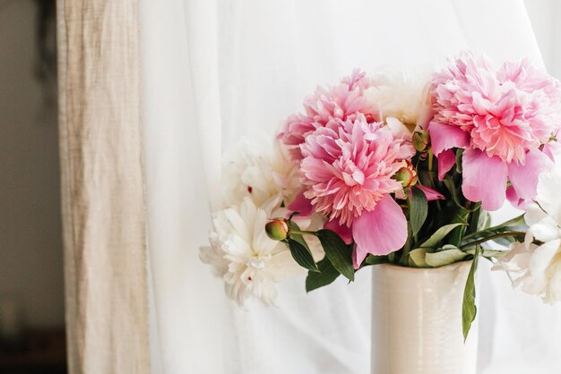 Stylish pink and white peonies in vase Hello spring Lovely peony bouquet in sunny light on rustic wooden window sill Happy Mothers day greeting card Happy valentines day