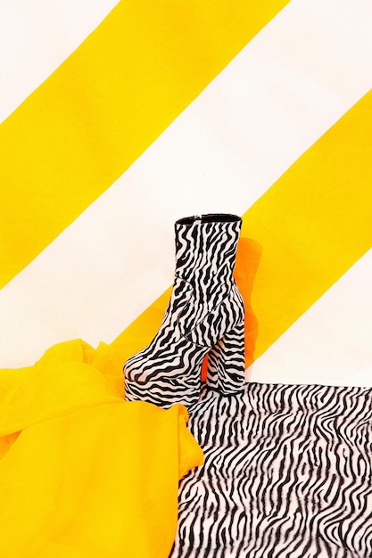 Stylish platform boots on bright striped yellow background. Tropical exotic creative minimal concept. Yellow and zebra print mixed. Still life fashion scene