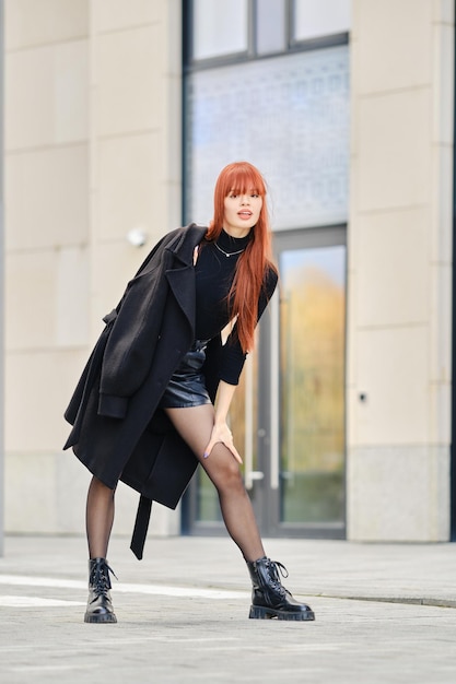 Stylish and playful woman in coat posing on the street