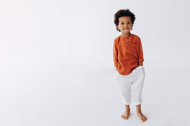 세련된 린넨 옷을 입은 곱슬곱슬한 3세 소년의 세련된 초상화