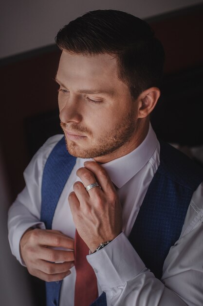 The stylish portrait of the groom preparing for the wedding ceremony in the morning. Morning of the groom. Morning preparation of the groom.