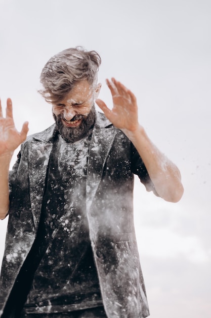 stylish portrait of a young bearded man in black clothes, The man is strewn with white matter