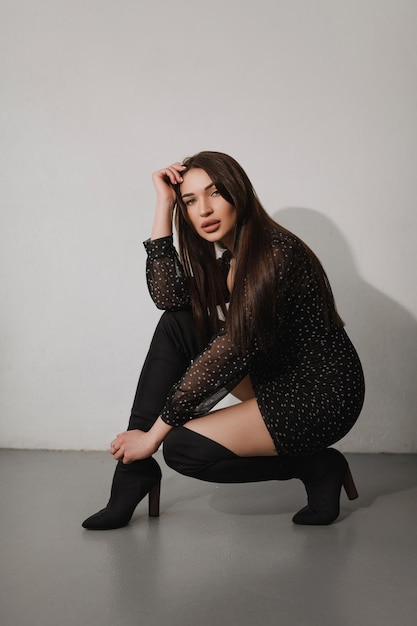 Stylish posing of a young girl in black clothes on a white background