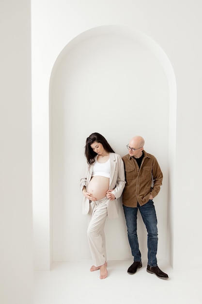 Stylish pregnant brunette in a beige trouser suit and a man in a shirt