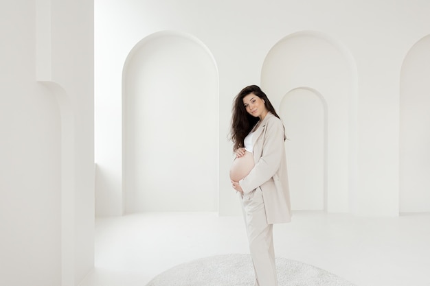 Photo stylish pregnant brunette girl with beige trouser suit