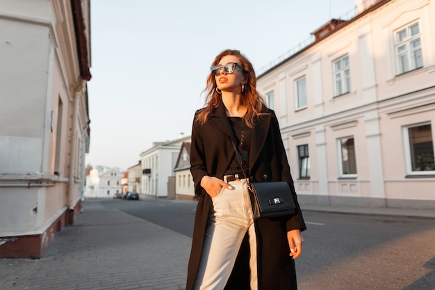 Elegante bella donna in outwear nero di moda cammina per strada