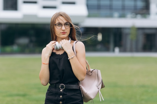 Donna graziosa alla moda in occhiali da sole e sorridente sulla strada