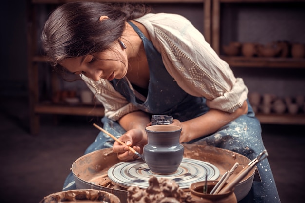 Stylish professional potter making ceramic pottery on wheel