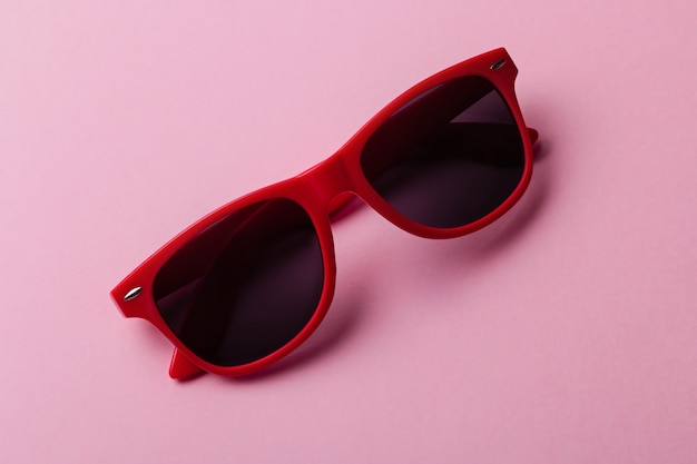 Stylish red sunglasses closeup on pink background