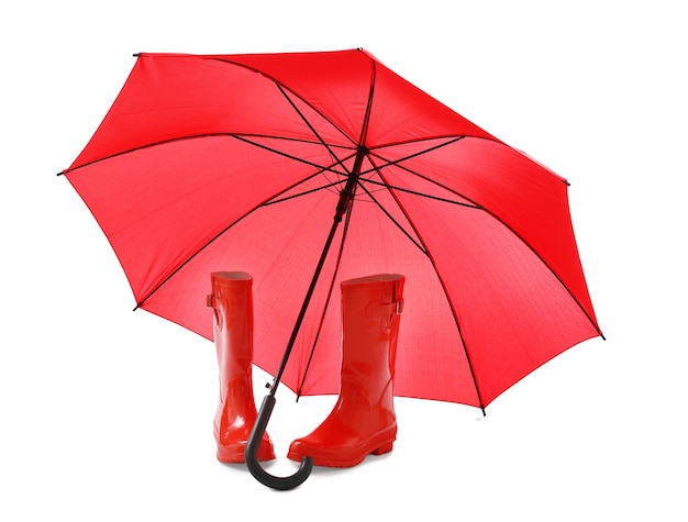 Stylish red umbrella and rubber boots on white background