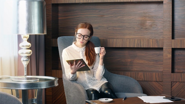 Stylish redhead girl working at home office.