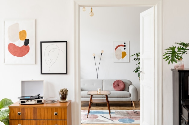 Stylish retro living room with vintage commode, poster frames, plants, decoration and elegant personal accessories