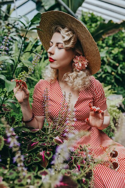 Stylish retro and vintage woman in garden full of tropic plants and flowers