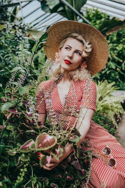 Stylish retro and vintage woman in garden full of tropic plants and flowers