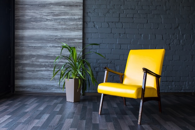 Stylish retro yellow chair in the gray room. Brick gray wall. Room.