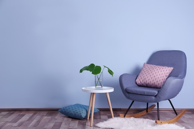 Stylish room interior with monstera leaves in vase on table