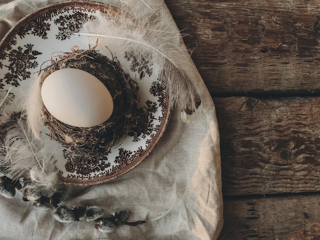 Stylish rustic Easter table setting Natural egg in nest feathers vintage plate napkin willow