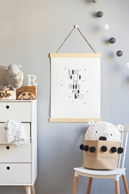 Stylish scandi childroom with wooden mock up photo frame, wooden and plush toys, boxes, blocks and accessories. Stars pattern on the background wall. Bright and sunny interior. Home decor.